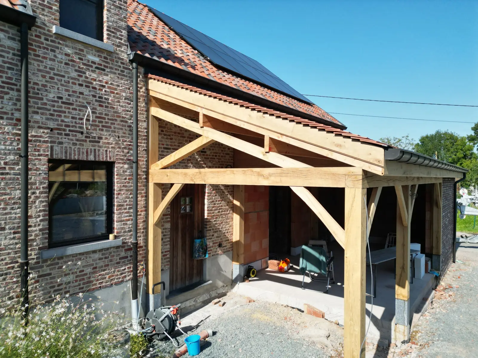 Dronebeeld van het eiken bijgebouw met Koramic tegelpannen naast de bestaande woning in Pajottegem